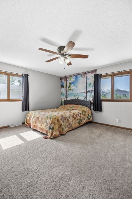 carpeted bedroom with a textured ceiling, ceiling fan, and baseboards