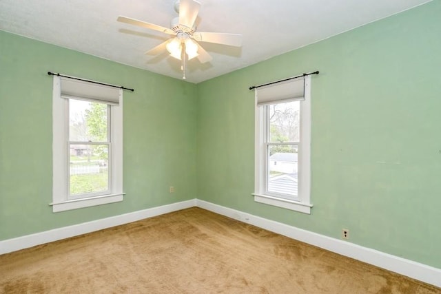 carpeted spare room featuring baseboards and a ceiling fan