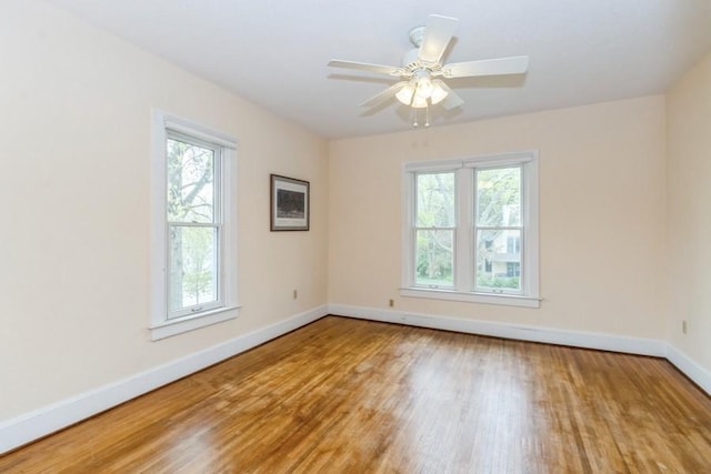 spare room with wood finished floors, baseboards, and a ceiling fan