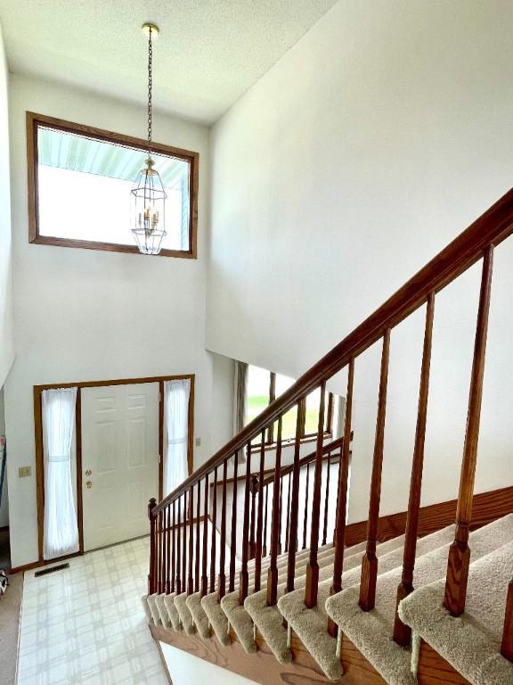 entryway featuring stairway, a chandelier, and tile patterned floors