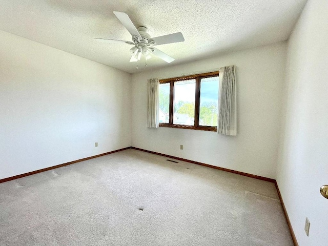 carpeted spare room with baseboards, a ceiling fan, and a textured ceiling