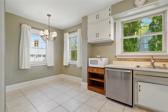 kitchen with stainless steel dishwasher, white microwave, a sink, a chandelier, and light countertops