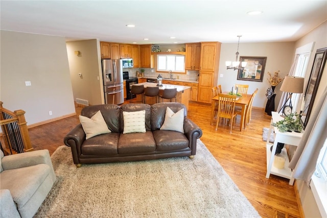 living area featuring light wood-type flooring, a chandelier, recessed lighting, and baseboards