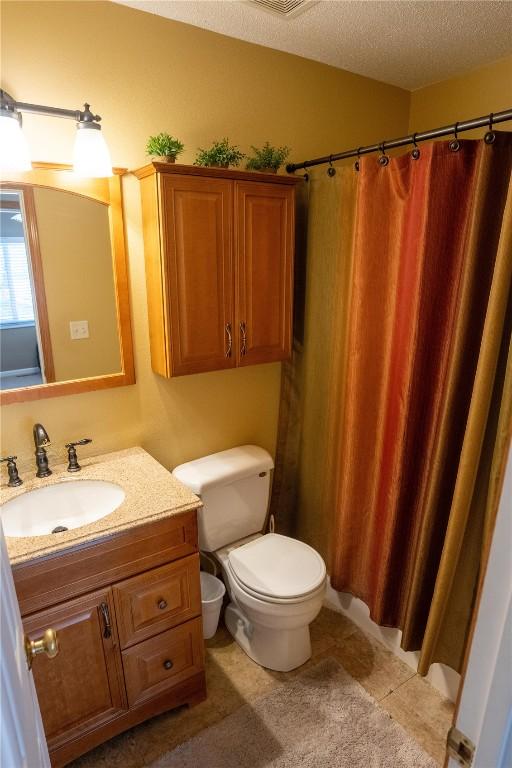 full bath featuring toilet, vanity, a textured ceiling, and curtained shower