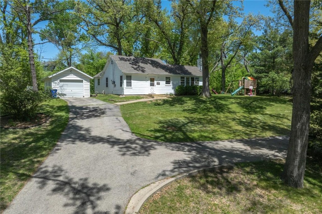 view of side of property with a garage, asphalt driveway, an outdoor structure, and a lawn