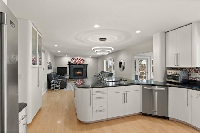 1659 Apache Dr NE, Solon, IA 52333 - kitchen featuring appliances with stainless steel finishes, a peninsula, dark countertops, white cabinets, and recessed lighting