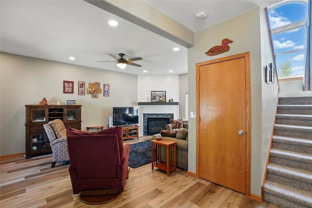 living area with stairs, light wood-type flooring, ceiling fan, a glass covered fireplace, and recessed lighting