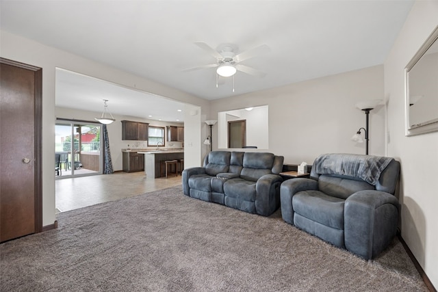 living area with light carpet and ceiling fan