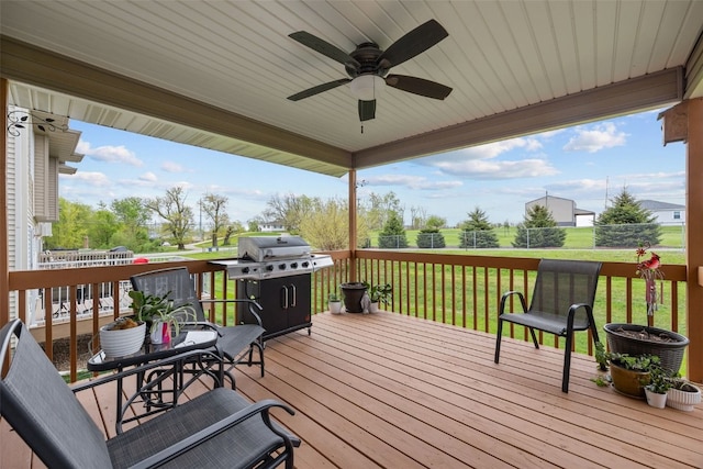 deck with grilling area, a ceiling fan, and a lawn