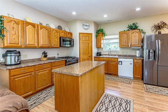 1100 Vernon Hill Blvd, Cedar Rapids, IA 52403 - kitchen featuring appliances with stainless steel finishes, a sink, light wood-style flooring, a center island, and brown cabinetry