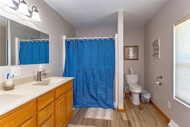 1100 Vernon Hill Blvd, Cedar Rapids, IA 52403 - bathroom with wood finished floors, toilet, double vanity, baseboards, and curtained shower