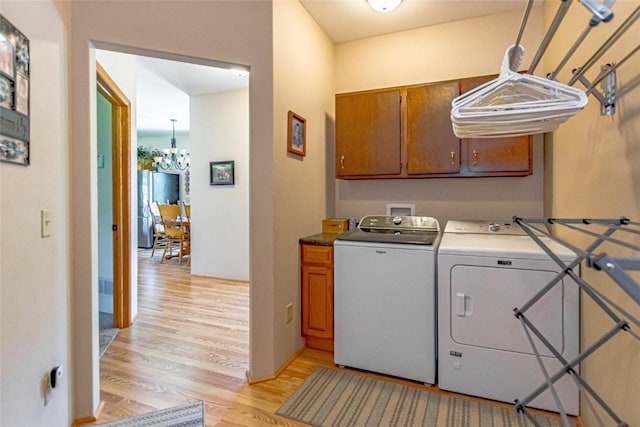 1100 Vernon Hill Blvd, Cedar Rapids, IA 52403 - laundry area featuring cabinet space, washer and dryer, light wood-style flooring, and a chandelier