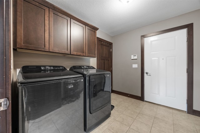 laundry room with washer and dryer, cabinet space, baseboards, and a textured ceiling
