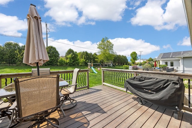wooden deck with a playground and outdoor dining area