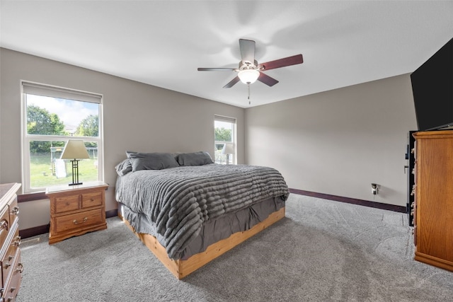 bedroom with light colored carpet, baseboards, and a ceiling fan