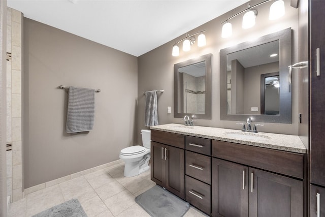 bathroom featuring toilet, double vanity, baseboards, and tile patterned flooring