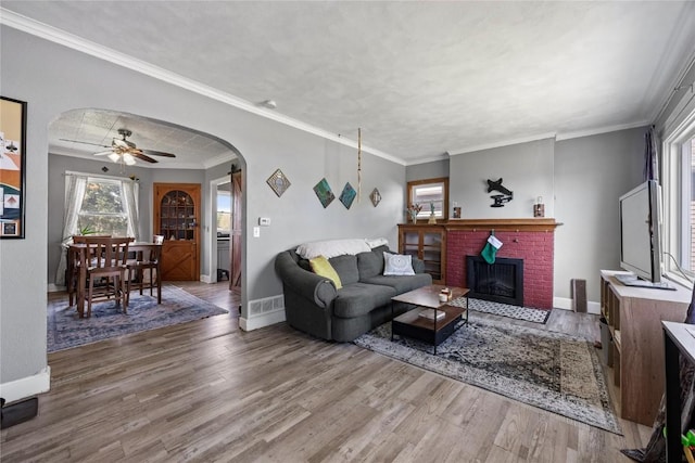 507 2nd St E, Newhall, IA 52315 - living area with arched walkways, wood finished floors, baseboards, a fireplace, and crown molding