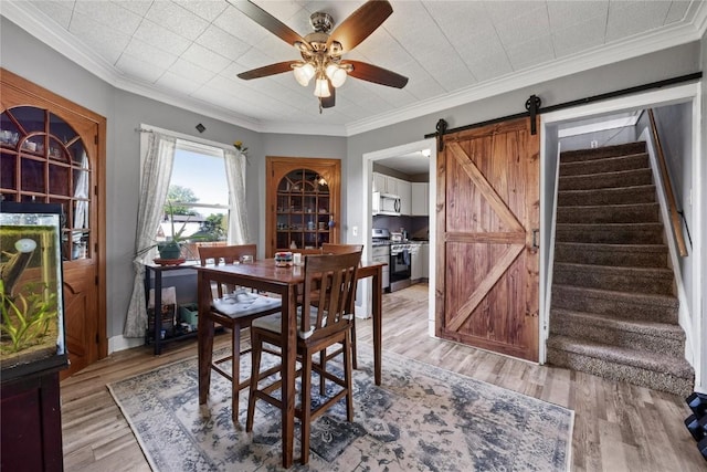 507 2nd St E, Newhall, IA 52315 - dining area featuring a ceiling fan, stairs, a barn door, and light wood finished floors