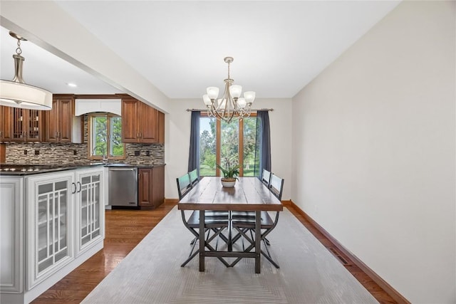 dining area featuring a chandelier, dark wood finished floors, and baseboards