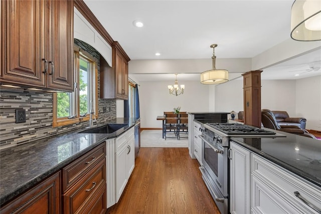kitchen with stainless steel range, dark wood-style flooring, decorative backsplash, a sink, and baseboards