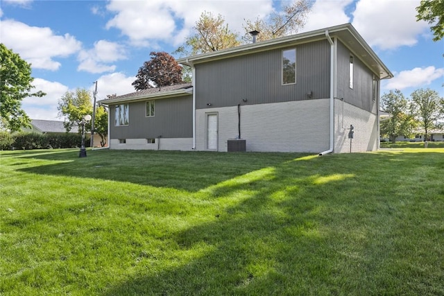 back of house with a lawn and brick siding