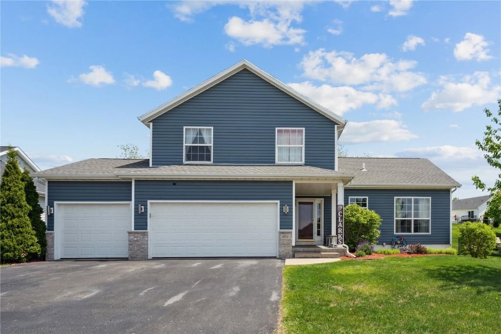 6911 Springwood Pl NW, Cedar Rapids, IA 52404 - traditional-style house featuring asphalt driveway, a front yard, and a garage