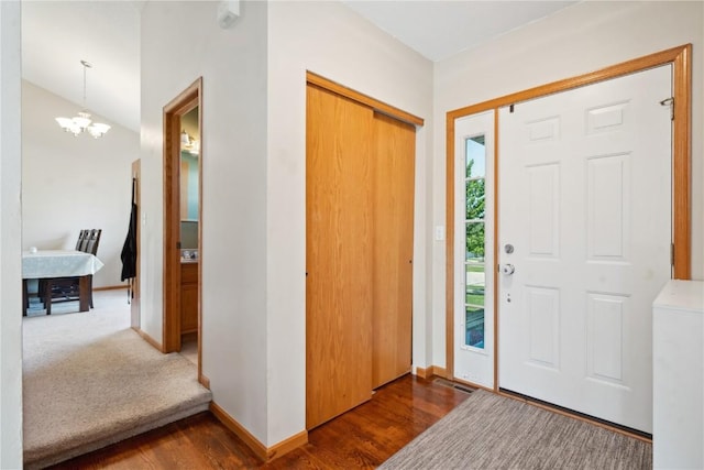 entrance foyer with dark wood-style flooring, a chandelier, and baseboards