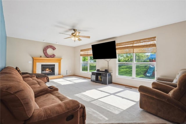 carpeted living area with a ceiling fan, baseboards, and a glass covered fireplace