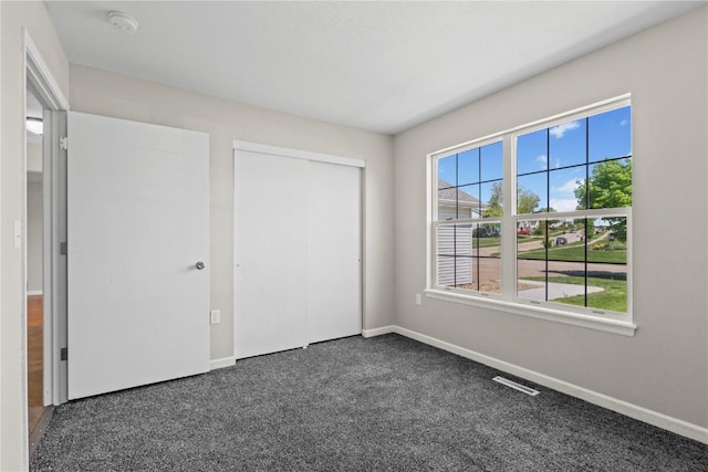 unfurnished bedroom with multiple windows, baseboards, and carpet