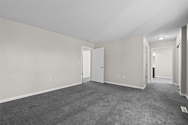 empty room with dark colored carpet and baseboards