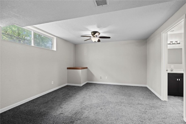 carpeted empty room featuring ceiling fan, a sink, a textured ceiling, and baseboards