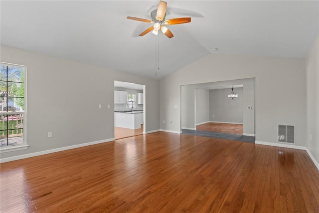 unfurnished living room featuring a ceiling fan, vaulted ceiling, a chandelier, wood finished floors, and baseboards