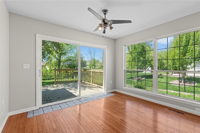 spare room featuring baseboards, ceiling fan, plenty of natural light, and hardwood / wood-style flooring
