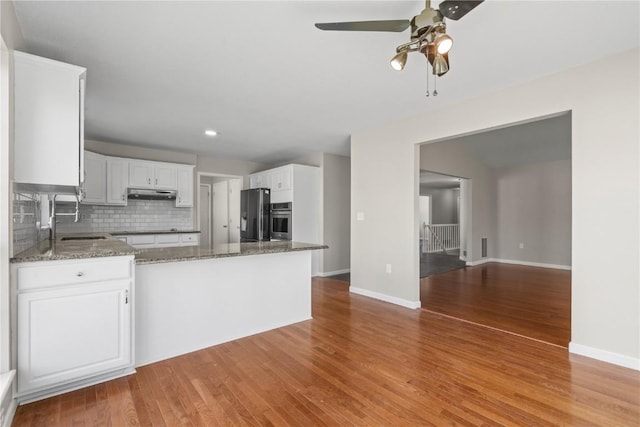 kitchen featuring a sink, oven, a ceiling fan, wood finished floors, and refrigerator with ice dispenser
