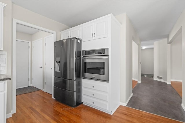 kitchen featuring stainless steel appliances, white cabinets, and dark wood-type flooring