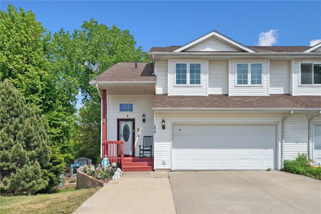 view of front facade featuring concrete driveway, a shingled roof, and a garage