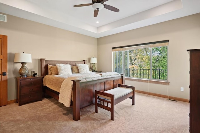 bedroom with light carpet, baseboards, a raised ceiling, and a ceiling fan
