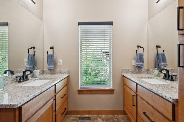 bathroom featuring two vanities and baseboards