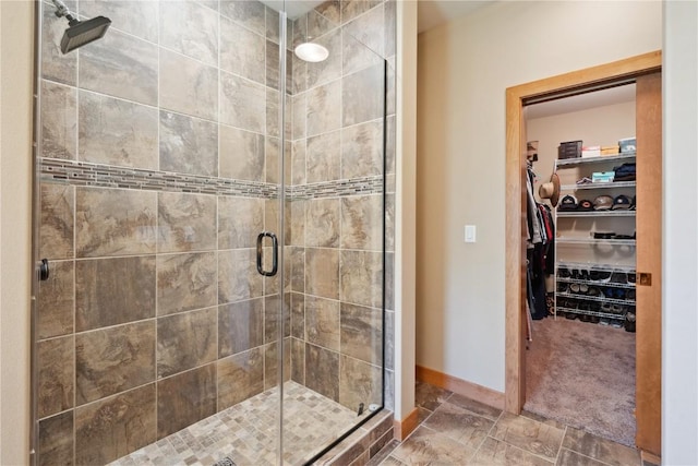 full bathroom featuring a shower stall, a walk in closet, and baseboards