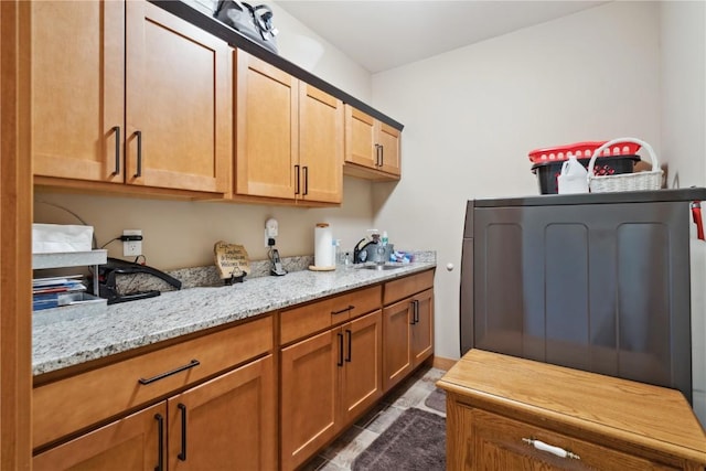 kitchen featuring a sink, light stone countertops, and washer / dryer