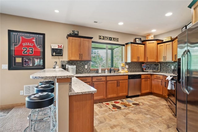 kitchen featuring appliances with stainless steel finishes, a peninsula, a kitchen bar, backsplash, and recessed lighting