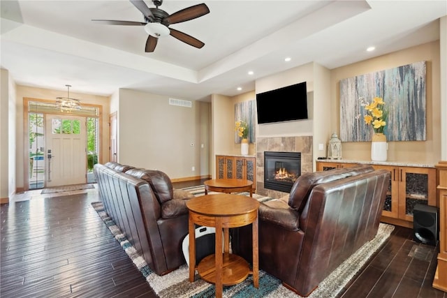 living room featuring a tiled fireplace, dark wood finished floors, baseboards, recessed lighting, and ceiling fan