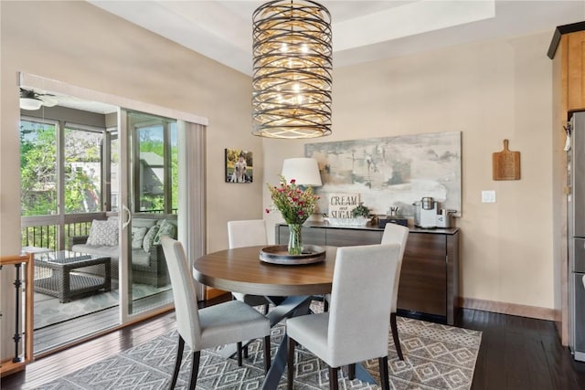 dining area with dark wood-style flooring, baseboards, and a chandelier