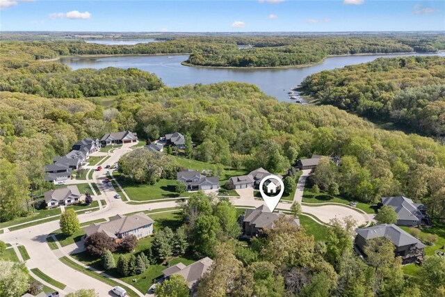 aerial view of property's location featuring a forest, a nearby body of water, and nearby suburban area