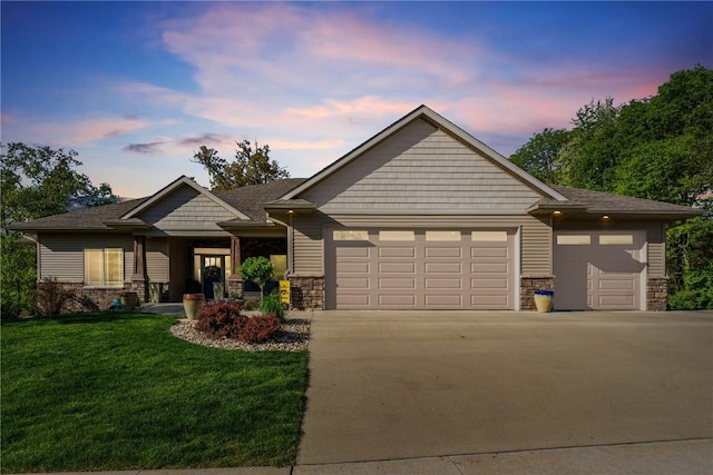 view of front of property featuring stone siding, a garage, driveway, and a front lawn
