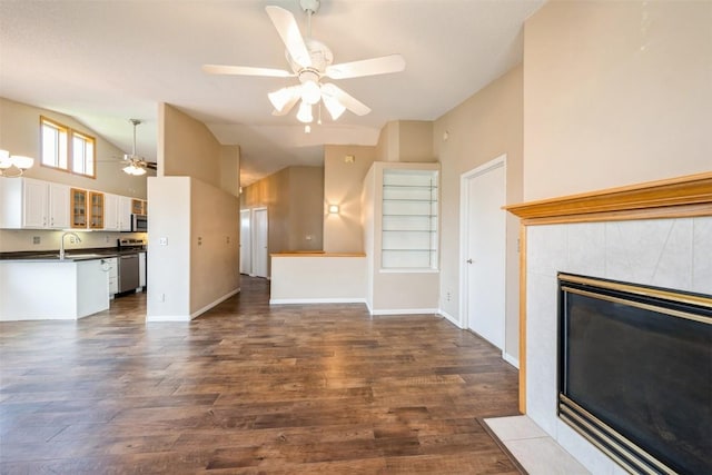 unfurnished living room featuring ceiling fan, lofted ceiling, a sink, dark wood-style flooring, and a tiled fireplace