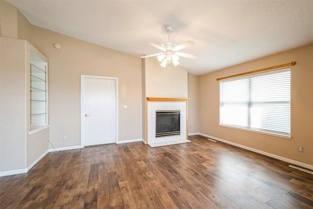 unfurnished living room featuring a ceiling fan, a tiled fireplace, wood finished floors, and baseboards