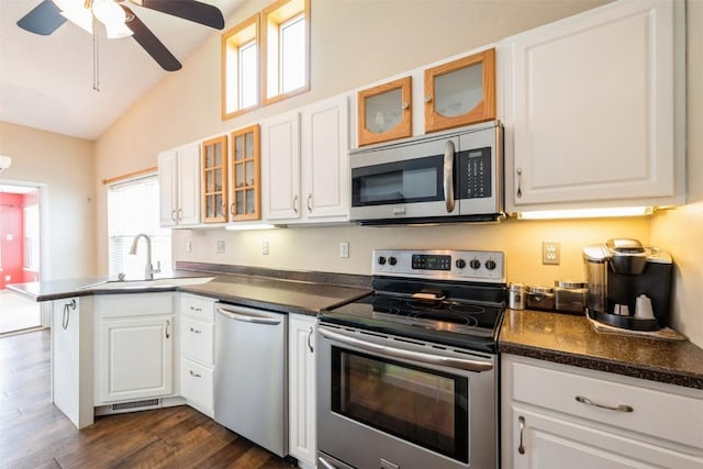 kitchen featuring stainless steel appliances, a sink, a peninsula, white cabinetry, and lofted ceiling