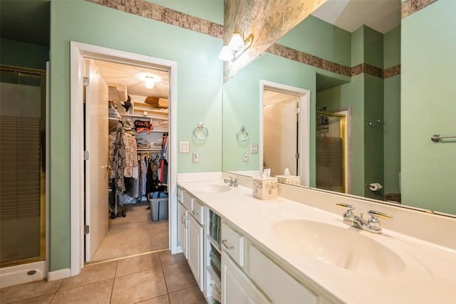full bathroom featuring a stall shower, tile patterned floors, a spacious closet, double vanity, and baseboards