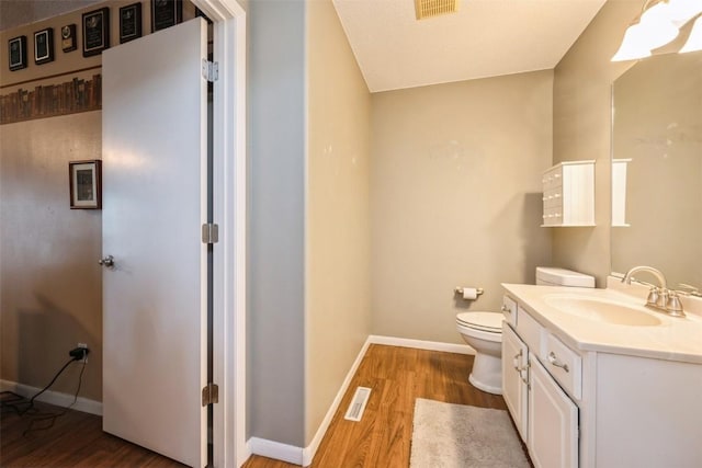 bathroom with wood finished floors, toilet, vanity, and baseboards